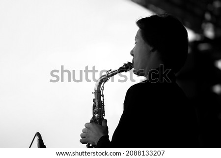 Musician man in a black shirt plays the saxophone .Silhouette on a white background