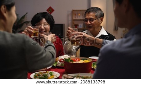 over shoulder shot with selective focus senior couple grandfather and grandmother making toast to family members, celebrating spring festival while having big meal on new year's eve Royalty-Free Stock Photo #2088133798