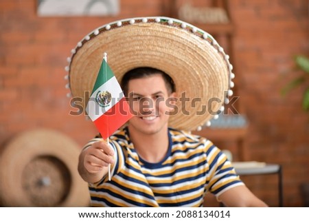 Handsome man in sombrero hat with Mexican flag at home