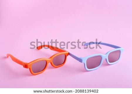 Blue and orange 3D glasses on a pink background. Front-top view. 