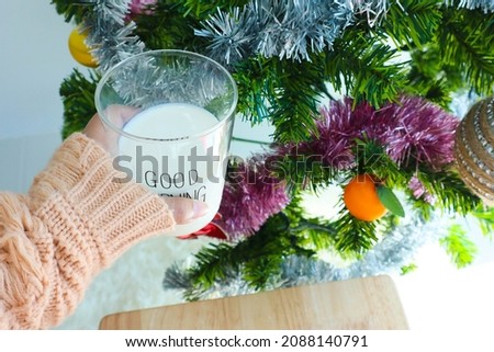 Woman's holding glass of milk with christmas tree.