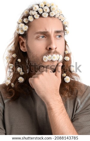 Portrait of handsome young man with flowers in hair on white background