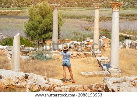 Tourist girl taking photos on smartphone of the ruins of Roman ancient city of Andriake in Demre, Turkey. Sightseeing and travel