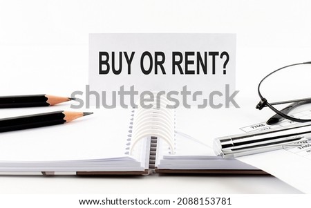 Text BUY OR RENT on paper card,pen, pencils, glasses,financial documentation on the table - business concept