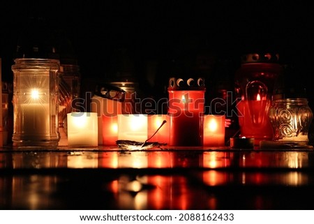 picture of lighting candles at cemetery. celebrating all saints day. november 1. autumn holidays. souls. memorial. lantern.