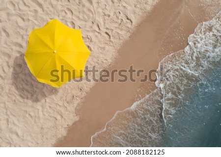 Yellow beach umbrella on sandy coast near sea, top view Royalty-Free Stock Photo #2088182125