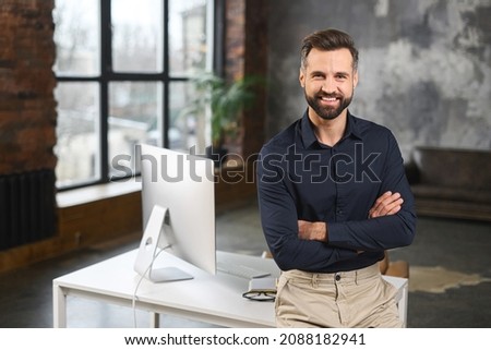 Proud and successful young businessman in smart casual wear with arms crossed, looking at camera with pleased smile, male entrepreneur, start-up owner stands in the office in confident pose Royalty-Free Stock Photo #2088182941