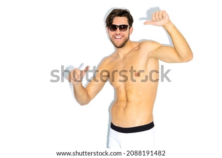 Caucasian Handsome Brunet Man in Sunglasses Gesturing With Both Hands While Posing in Underware Against White Background. Horizontal Image