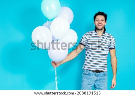Man Celebrating Anniversary of Business Company Aa a Part of Corporate Party While Carrying Colorful Airballoons Casual Clothing Poses Against Blue Background. Horizontal Image
