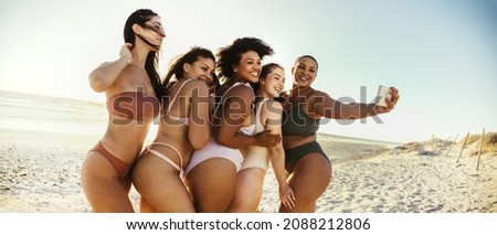 Making memories at the beach. Group of carefree young women smiling cheerfully while taking a picture together in the sun. Happy female friends having fun and enjoying their summer vacation.