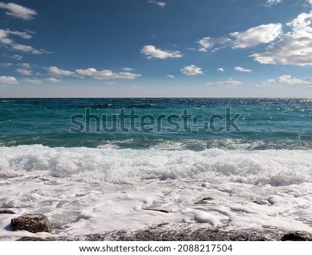 gorgeous waves and pebble sea beach under sunny cloudy skies