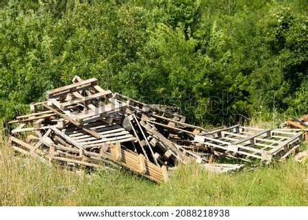 Heap of old wooden pallets, dump on the background of nature. High quality photo