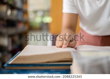 Young Asian women are searching for books and reading books on the tables and aisles of the college libraries to research and develop their academic and education self. Royalty-Free Stock Photo #2088225265