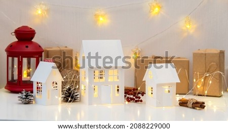 Childrens crafts made of white paper for Christmas, New Year. The decor of the houses is made of cardboard and garlands. Cozy atmosphere. Banner.