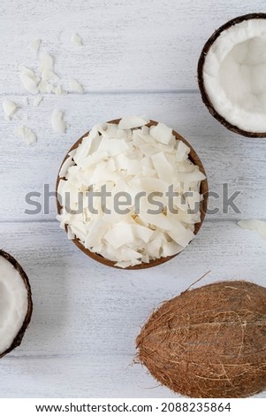 Coconut chips and coconuts on white wooden background top view Royalty-Free Stock Photo #2088235864