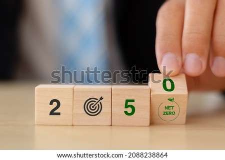 Net zero by 2050. Carbon neutral. Net zero greenhouse gas emissions target. Climate neutral long term strategy. No toxic gases. Hand flips wooden cubes with net zero icon in 2050 on smart background. Royalty-Free Stock Photo #2088238864