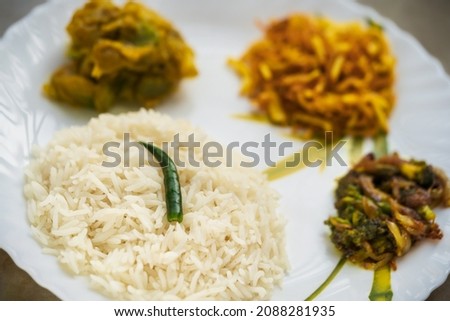 Typical Bengali thali background containing rice, dal, potato fries, vegetable curry and a green chili. Concept for Indian regional food, traditional homemade dish or meal. Royalty-Free Stock Photo #2088281935