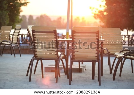 Closeup of outdoors cafe chairs and table at sunset on city street