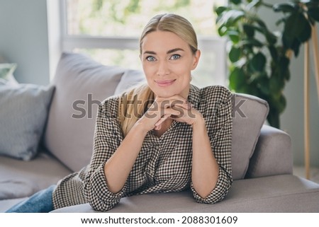 Photo of good mood mature lady sit divan in modern apartment touch hands chin speak video call followers