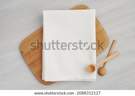White blank cotton kitchen towel mockup for design presentation, wooden spoons and cutting board. Royalty-Free Stock Photo #2088312127