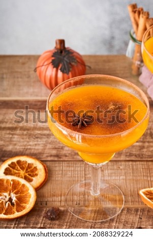 Pumpkin cocktail with cinnamon, orange juice and cocoa in glass mugs. Festive cocktail Halloween margarita. Pumpkin autumn drink for Halloween or Thanksgiving.