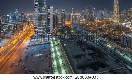 Panoramic view to Dubai's business bay towers aerial night timelapse. Rooftop view of some skyscrapers and new buildings under construction with parking
