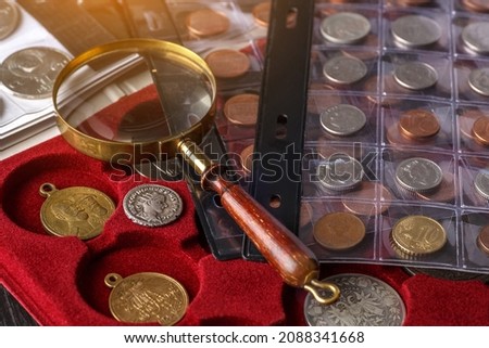Numismatics. Old collectible coins made of silver on a wooden table.Coins in the album.Collection of old coins. Magnifying glass Royalty-Free Stock Photo #2088341668