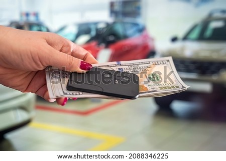 beautiful well-groomed female hands holding dollar bills and car keys in the car. The concept of buying and selling. Business concept.