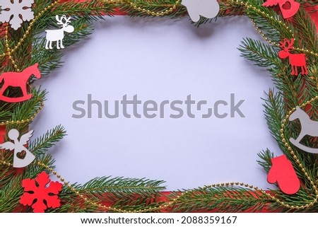Christmas card decorated with green Christmas tree branches and wooden toys of red and white color. Copyspace. Space for your text. The concept of congratulations on the holiday of different people