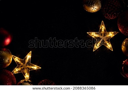 Golden, five-pointed stars, on a black background. Two golden stars and Christmas decorations, on a black background, with a copy space. Merry Christmas and Happy New Year.