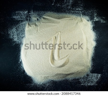 Greek letter iota written on a white sand with black background