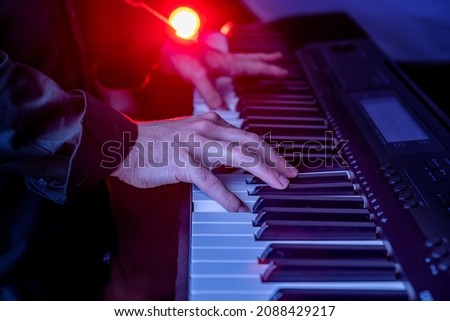 Male hands playing electric synthesizer Digital Piano, fingers pushing keys. Musician man piano player accompanist on black and white keyboards at a concert stage show. Performance poster, music cover