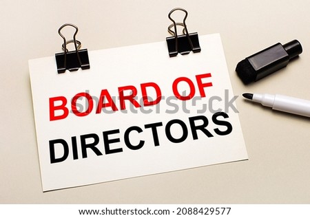 On a light background, a black open marker and on black clips a white sheet of paper with the text BOARD OF DIRECTORS