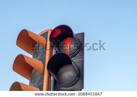 Red pedestrian lamp. Led Traffic light for pedestrian people. Orange unlit traffic light for car.￼ Focus on red person icon. Traffic regulation and urban transportation.