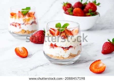 Berry dessert in glass with fresh strawberry, biscuit and whipped cream. Vegan lactose free dessert with alternative milk of coconut. Recipe of healthy organic dessert, cheesecake or berry trifle cake Royalty-Free Stock Photo #2088457198