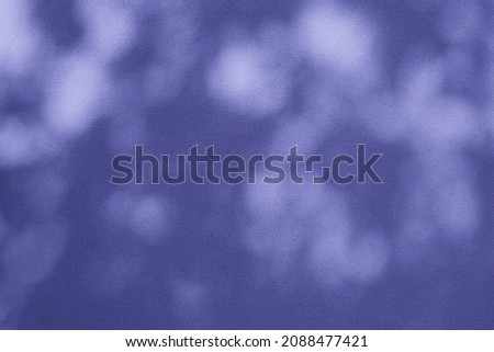 Abstract leaves shadow background with light bokeh toned in trendy pantone Very Peri color of the Year 2022,Abstract shadow background of natural leaves tree branch falling on wall