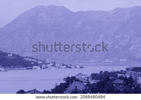 view of medieval tiled roofs of stone houses with windows and wooden shutters in the old town of Kotor, Montenegro toned in trendy Very Peri pantone color of the Year 2022