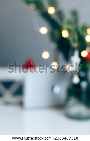 Blurred background of Christmas decorations, a Christmas tree with toys and a laptop at the table. A vertical photo is ideal for social media. Christmas background
