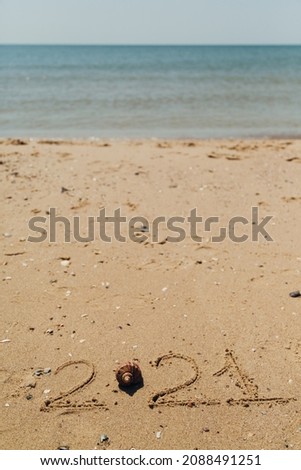 Text 2021 Written on the Sand of a Beach. The Sea on a Background of Letters