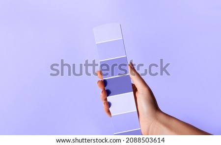 Hand holding Color samples palette design catalog. New 2022 trending PANTONE 17-3938 Very Peri color Royalty-Free Stock Photo #2088503614