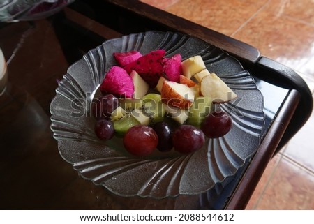  Pieces of assorted colorful fruits that have been sliced ​​to be ready to eat, in a glass poring.  Consists of apples, dragon fruit, kiwi and grapes.  Isolated