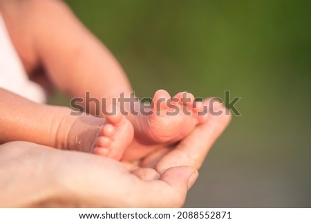 Mommy hand hold small new born baby feet close up