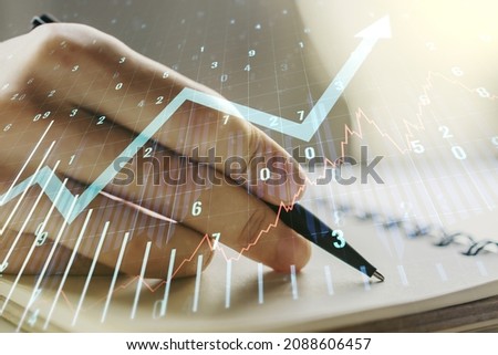 Multi exposure of abstract financial graph with upward arrow and man hand writing in diary on background, financial and trading concept
