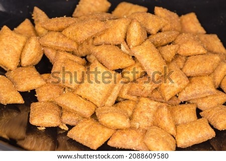 Small heap of dry cat food in the form of the small pillows poured in black plastic bowl, close-up in selective focus
