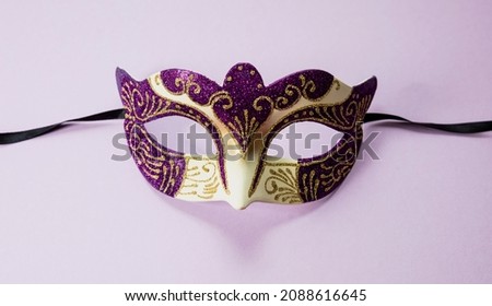 Carnival Venetian mask purple color with glitter on vibrant pink background. Traditional festival female disguise, masquerade
