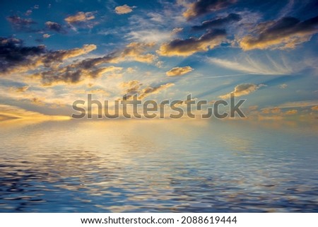 lovely reflection of the evening cloudy sky in the calm sea water surface