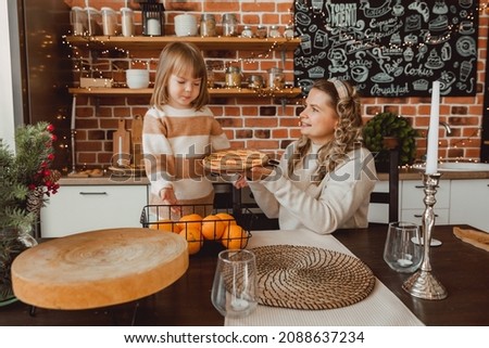 mother and child are sitting in the kitchen at the table with pie and oranges
