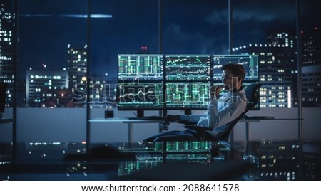Financial Analyst Working on a Computer with Multi-Monitor Workstation with Real-Time Stocks, Commodities and Exchange Market Charts. Businessman Works in Investment Bank Downtown Office at Night. Royalty-Free Stock Photo #2088641578