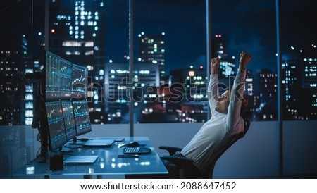 Stock Market Day Trader Working on Computer with Multi-Monitor Workstation with Real-Time Investment, Commodities and Foreign Exchange Charts. Successful Businessman Punches Air for Winning a Trade. Royalty-Free Stock Photo #2088647452