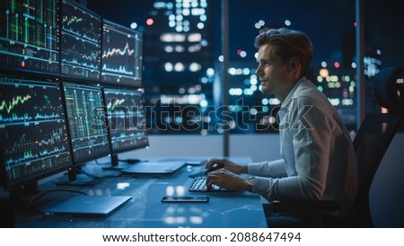 Financial Analyst Working on a Computer with Multi-Monitor Workstation with Real-Time Stocks, Commodities and Exchange Market Charts. Businessman Works in Investment Bank Downtown Office at Night. Royalty-Free Stock Photo #2088647494